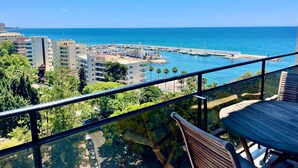 Un balcon avec vue sur un port de plaisance, des immeubles et la mer.
