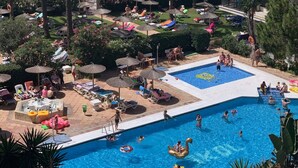 Un complexe hôtelier doté d’une piscine entourée de palmiers et de chaises longues.