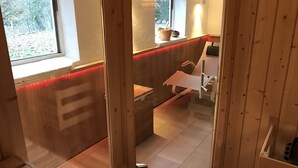 Een houten interieur met een raam, een bank, een stoel en een klein tafeltje.