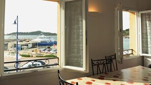 A room with a balcony overlooking a marina, a table with a floral tablecloth, and a chair. - Comfortable duplex on the peninsula of Giens facing Porquerolles sea view (La Tour Fondue)
