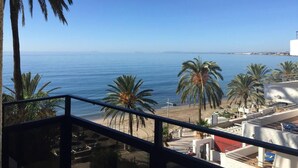 Ein Balkon mit Blick auf das Meer, Palmen und einen Strand.