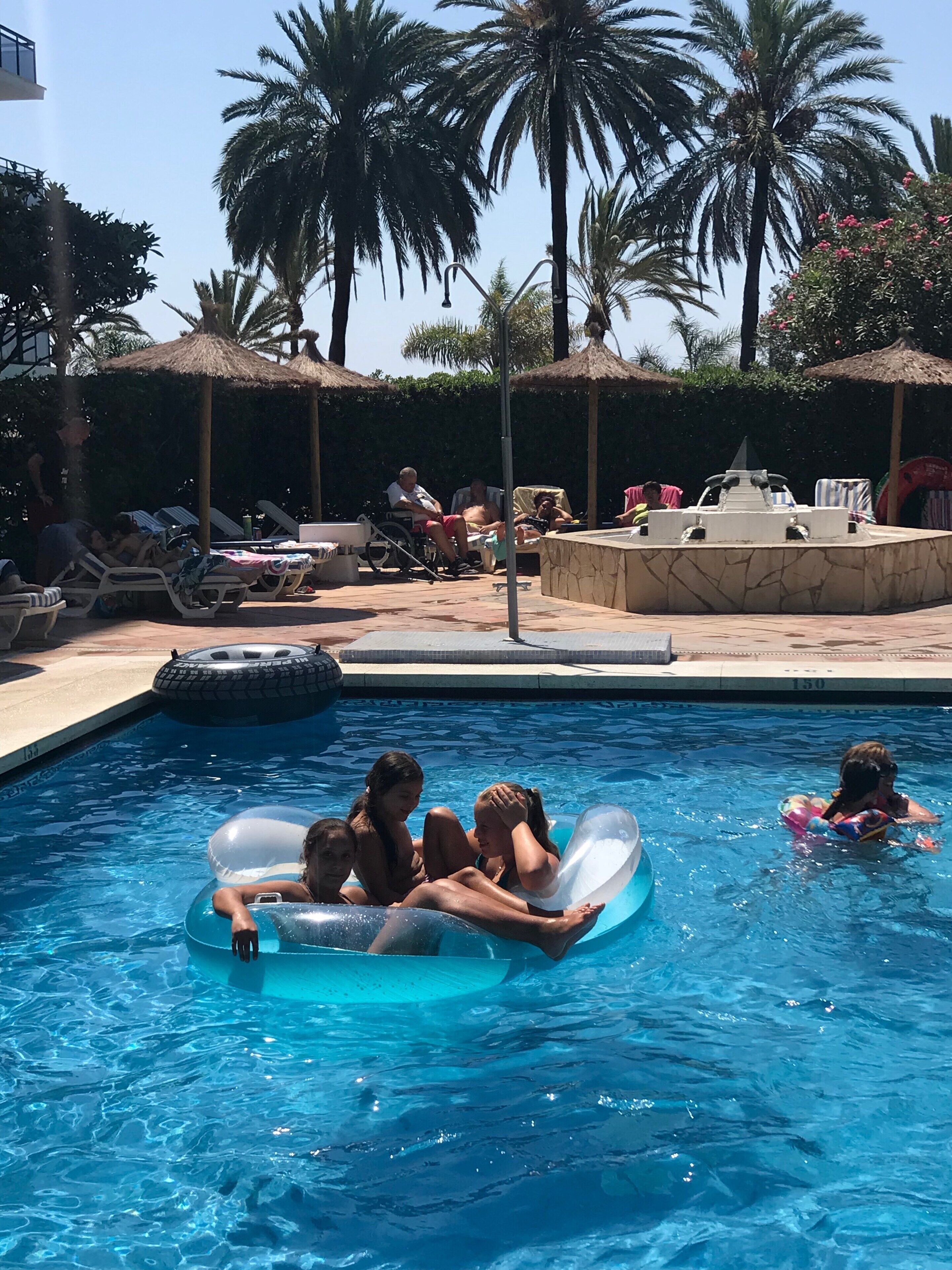 A swimming pool with lounge chairs and palm trees.