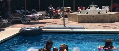 A swimming pool with lounge chairs and palm trees.