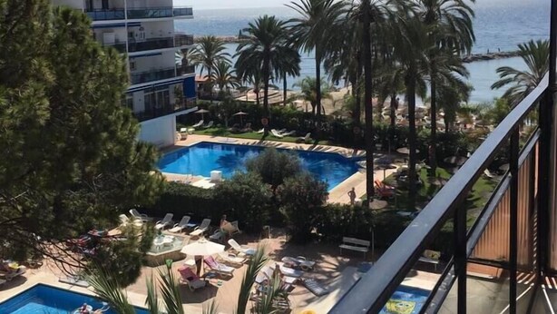 Ein Hotel mit Poolbereich, Palmen und Meerblick.