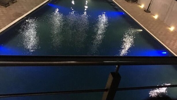 Une piscine agrémentée de jeux d’eau et entourée de chaises longues.