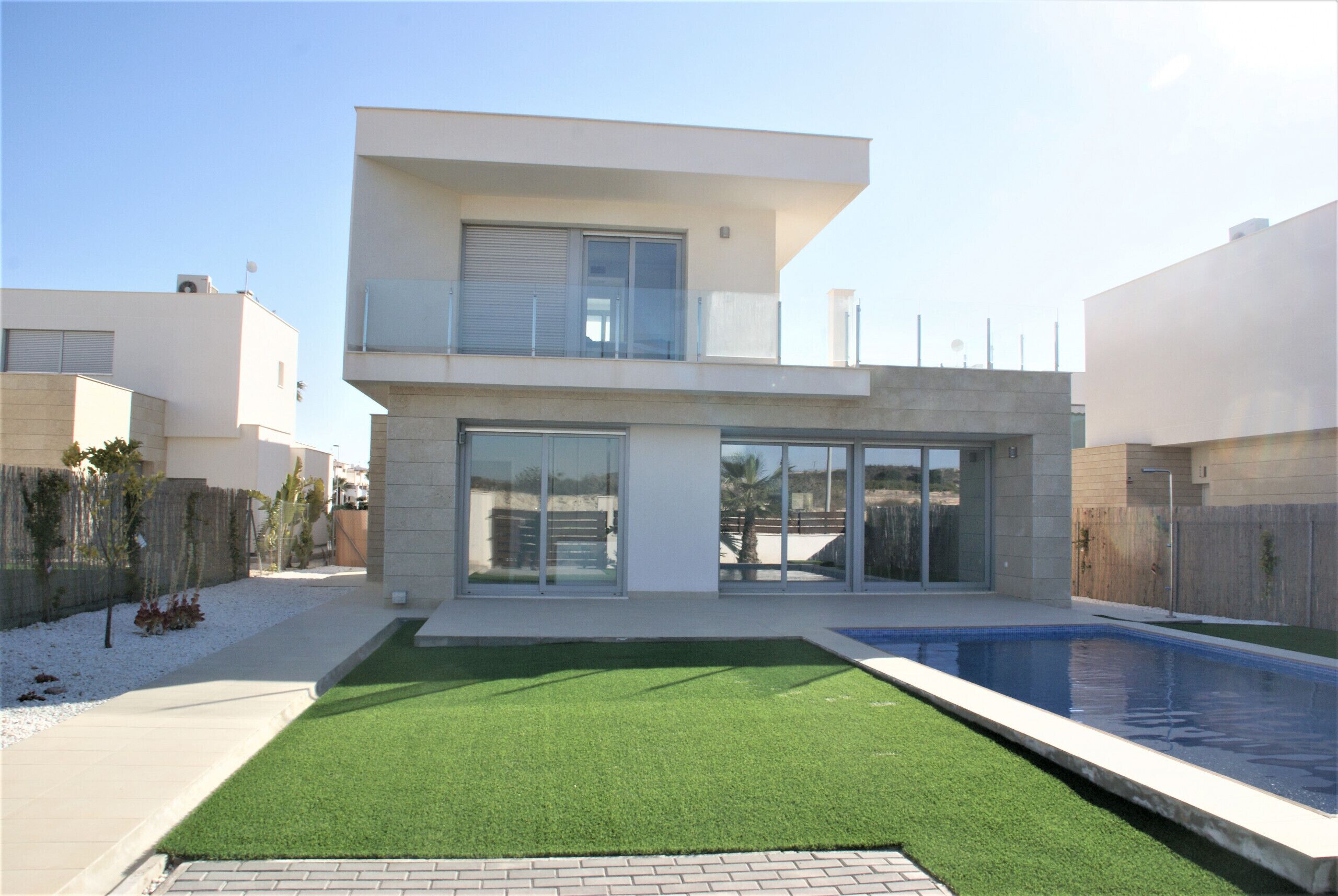 Ein modernes, zweistöckiges Haus mit Swimmingpool, großen Glasfenstern und einem gepflegten Rasen.