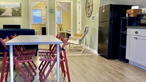 Eine moderne Küche mit einem schwarzen Kühlschrank, weißen Schränken und einem Essbereich mit Tisch und Stühlen.