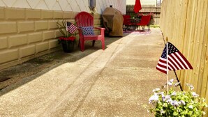Eine Terrasse mit einem roten Stuhl, einem Grill und amerikanischen Flaggen.
