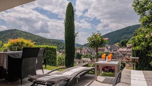 A terrace with a lounge chair and table, overlooking a village with traditional houses and a mountain backdrop. - Beautiful apartment Casa Rossa in Neckarsteinach am Neckar. (Neckarsteinach)