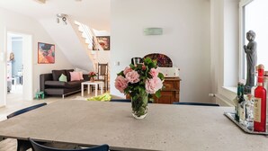 A spacious living area with a dining table, a sofa, and a staircase leading to an upper level.