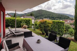 An outdoor patio with a table and chairs, surrounded by greenery and a view of a hillside. - Beautiful apartment Casa Rossa in Neckarsteinach am Neckar. (Neckarsteinach)