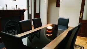 A dining table with chairs, a lit candle, and a fireplace in the background. - Napier Cottage - Cozy Hills Retreat (Hawthorndene)