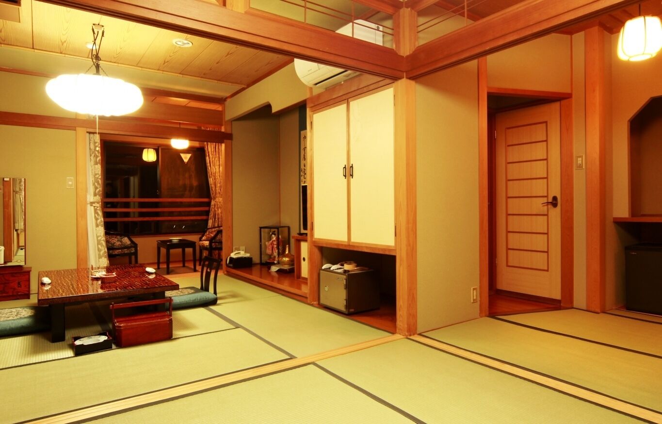 Ein traditioneller japanischer Raum mit Tatami-Bodenbelag, einem niedrigen Tisch mit Kissen, einem Schrank und einer Schiebetür.
