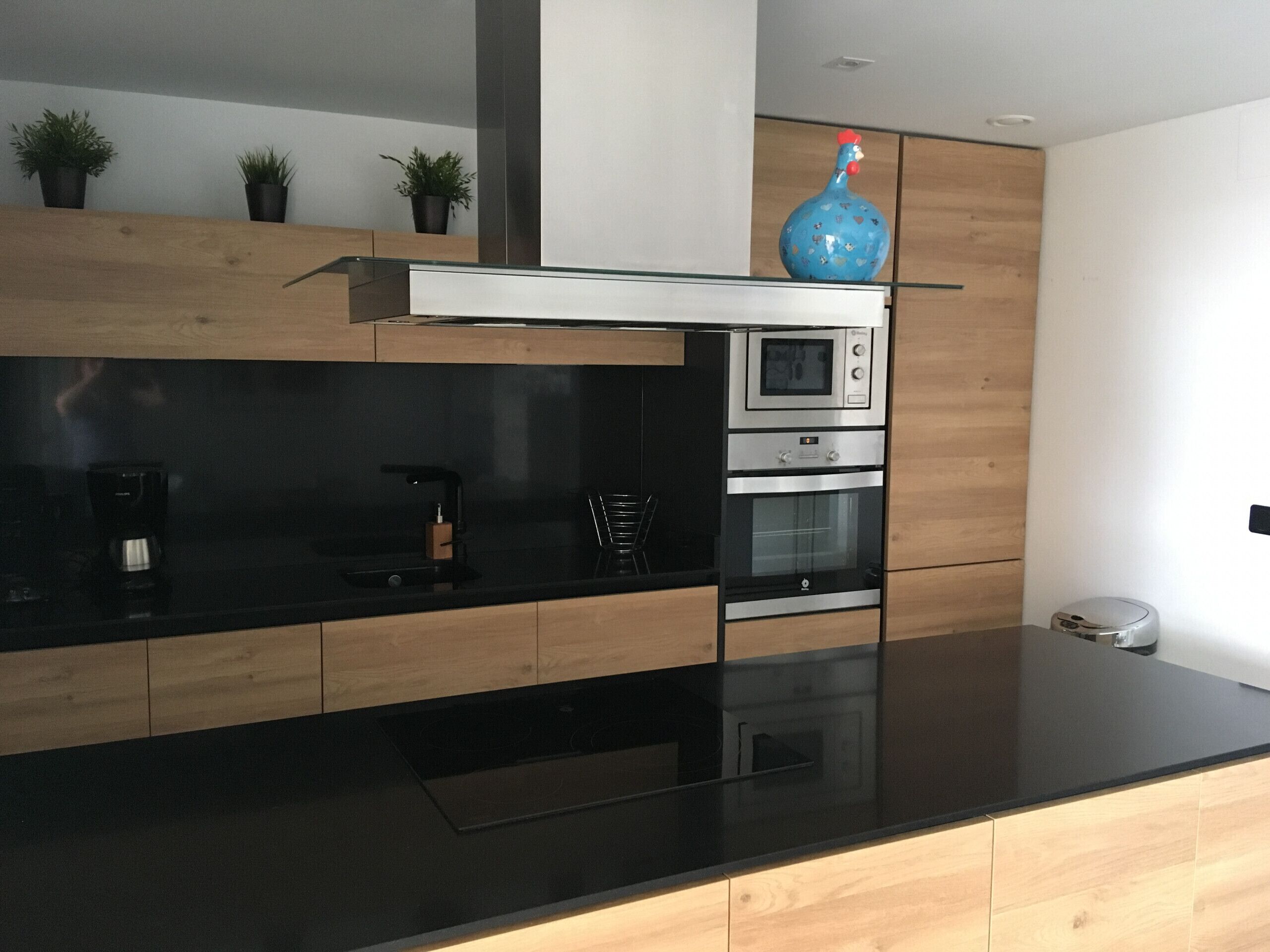 A modern kitchen with a black countertop, wooden cabinets, and stainless steel appliances.