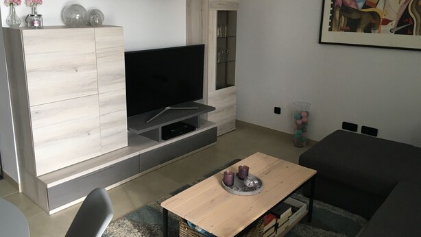 Un salon moderne avec un téléviseur à écran plat, une table basse en bois, un canapé et un tableau accroché au mur.