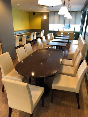 A conference room with a large oval table surrounded by chairs, large windows, and pendant lighting. - Gran Hotel (Shingu)