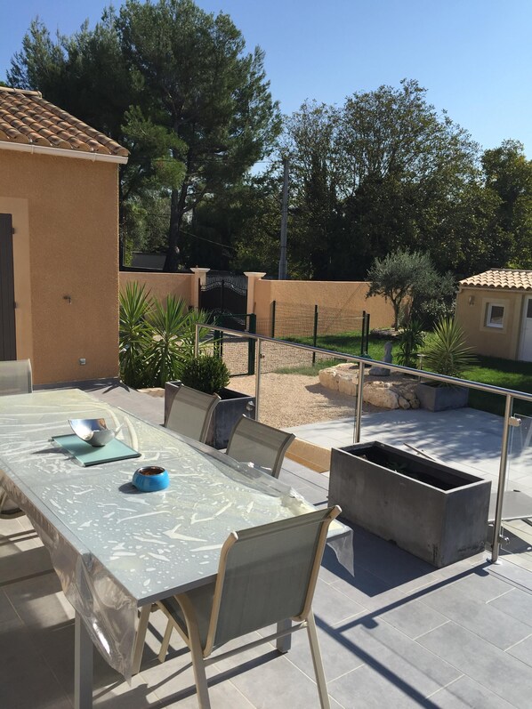 An outdoor patio with a table and chairs, a small garden area, and a fenced enclosure.