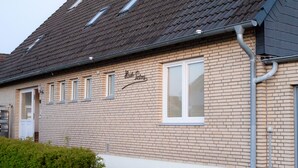 A brick building with a sign reading "Kauf Lehm" and a window with a white frame. - Beautiful new, modern apartment in Grömitz, 43sqm (Grömitz)