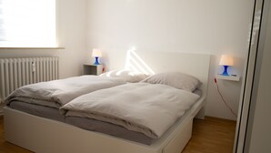A modern bedroom with a bed, bedside tables, and a window. - Beautiful new, modern apartment in Grömitz, 43sqm (Grömitz)