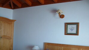 Ein Schlafzimmer mit einem großen Bett, zwei Kissen, einem Nachttisch mit Lampe, einem Holzschrank und einem gerahmten Bild an der Wand.