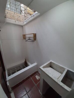Una habitación pequeña y estrecha con tragaluz, perchero, ventana pequeña y suelo de baldosas.