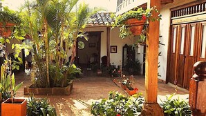 A courtyard with potted plants, a tiled floor, and a wooden pergola.