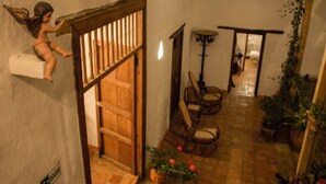 A cozy interior with a wooden staircase, a dining area with wicker chairs, and potted plants.