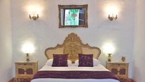 A bed with an ornate headboard, two bedside tables with lamps, and a mirror on the wall.