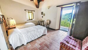 Een slaapkamer met een bed, een tafeltje, een stoel en uitzicht op een balkon.