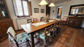 Een eetgedeelte met een houten tafel, stoelen en een kroonluchter.