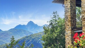 Een stenen gebouw met een balkon met uitzicht op een bergachtig landschap.