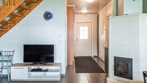 Un salon avec une télévision, un escalier en bois et une cheminée.