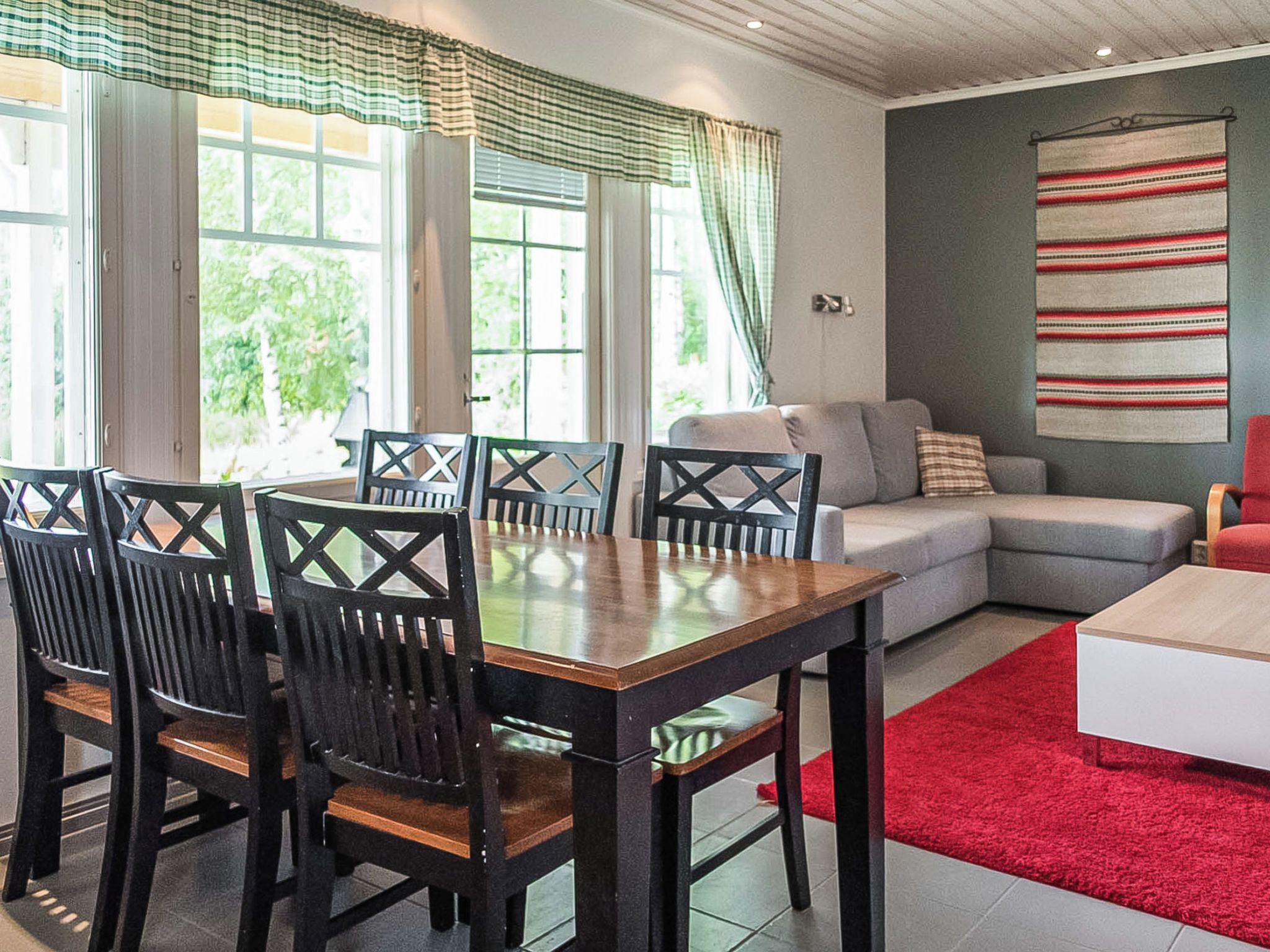 Un coin repas avec une table et des chaises, un canapé et un tapis rouge.