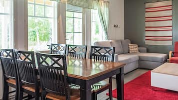 Un coin repas avec une table et des chaises, un canapé et un tapis rouge.