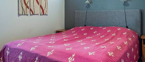 Ein Schlafzimmer mit einem Bett, einem Fenster und einer Wandleuchte.