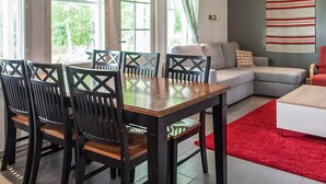 Un coin repas avec une table et des chaises en bois, un canapé et un tapis rouge.