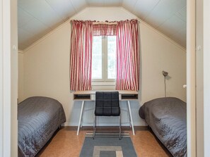 Una camera del dormitorio con due letti, una scrivania e una sedia.