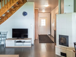 A living room with a TV, a fireplace, and a staircase. - Hintrekki by Interhome (Kaustinen)