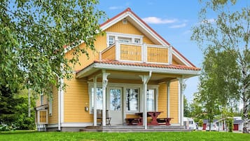 Une maison jaune avec un balcon, une véranda et un toit rouge.