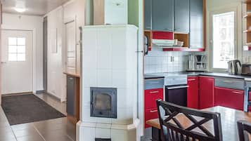 A kitchen with a built-in stove, red cabinets, and a dining area with a table and chairs.