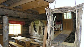 A rustic interior with wooden walls, a bench, a table, and a hanging light fixture. - Rantapuro by Interhome (Kuusamo)