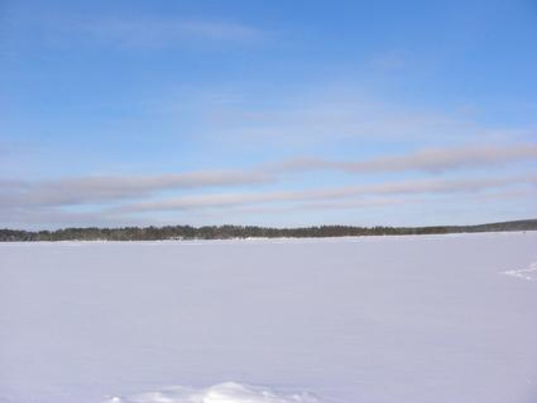 A vast, flat, snow-covered landscape with a clear sky.