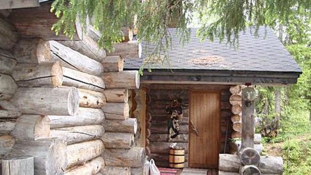 A rustic log cabin with a wooden door, a small porch, and a wooden bench. - Rantapuro by Interhome (Kuusamo)