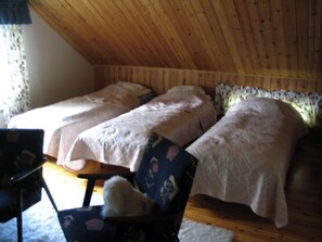 Een gezellige kamer met twee bedden, een houten plafond en een stoel met een deken.