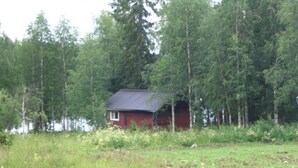 A small red cabin surrounded by tall trees and a grassy field. - Rantala by Interhome (Kuusamo)