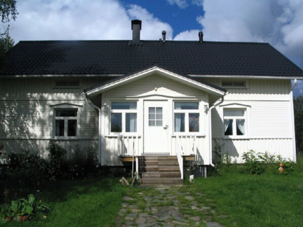 Een tweelaags huis met een donker dak, witte buitenmuren en een voortuin.