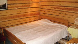 A wooden cabin room with a single bed, a small table with a lamp, and a framed picture on the wall. - Rantala by Interhome (Kuusamo)