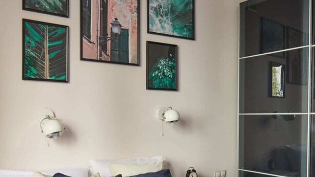 A hotel room with a bed, pillows, a nightstand, a clock, and artwork on the wall. - Plac Zbawiciela Hipster Apartment (Warsaw)