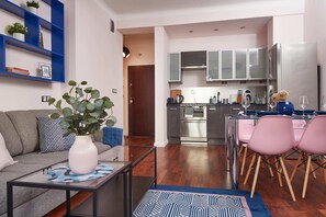 A modern living room with a sofa, coffee table, and a dining area with pink chairs. - Plac Zbawiciela Hipster Apartment (Warsaw)