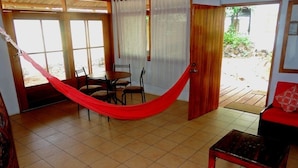 A room with a hammock, a dining table with chairs, a sofa, and a view of the outside. - GALAPAGOS CASA MARINA (Puerto Ayora)